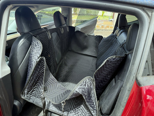 Black quilted dog backseat extender installed in a red Tesla Model Y