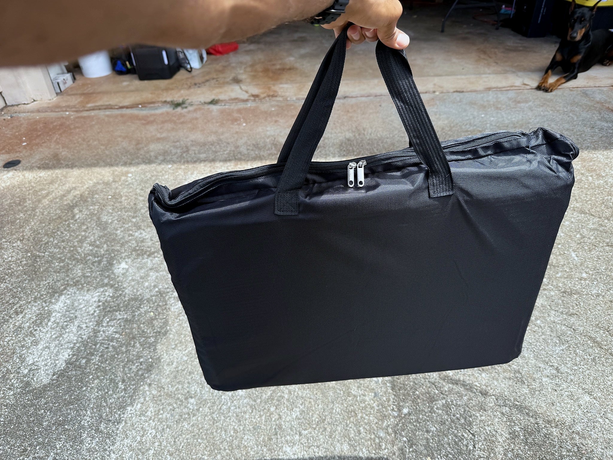 Folded dog backseat extender inside its carrying bag